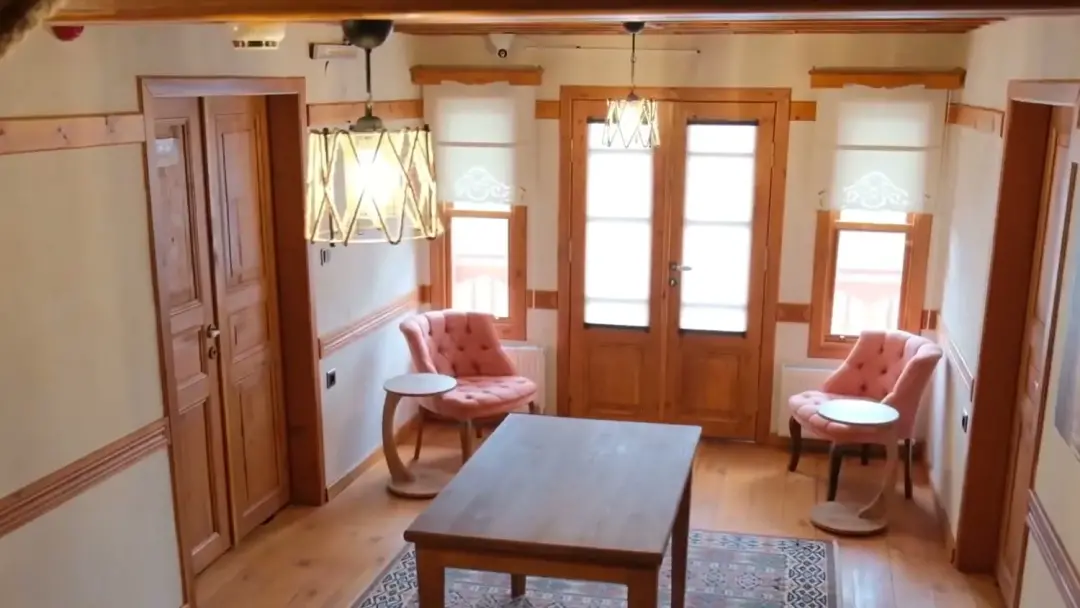 Ahşap kapılar, ipli avize ve iki koltuklu oturma köşesi